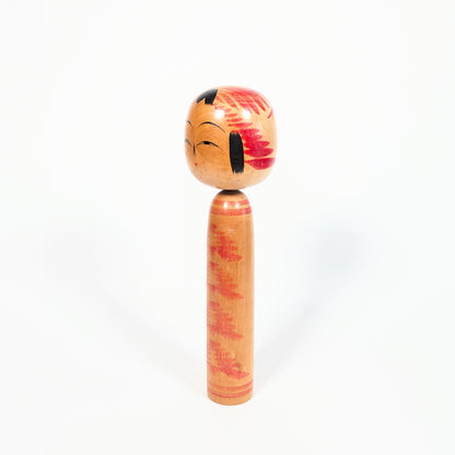 Kokeshi vintage style Togatta, profil trois quarts avec décor tegara sur la tête et motif kasanegiku rouge sur bois naturel.