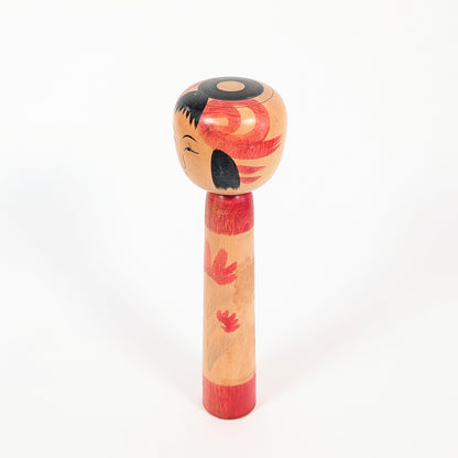 Profil d’une dento kokeshi Tsuchiyu-kei, coiffure noire stylisée, décor rouge et artisanat japonais authentique
