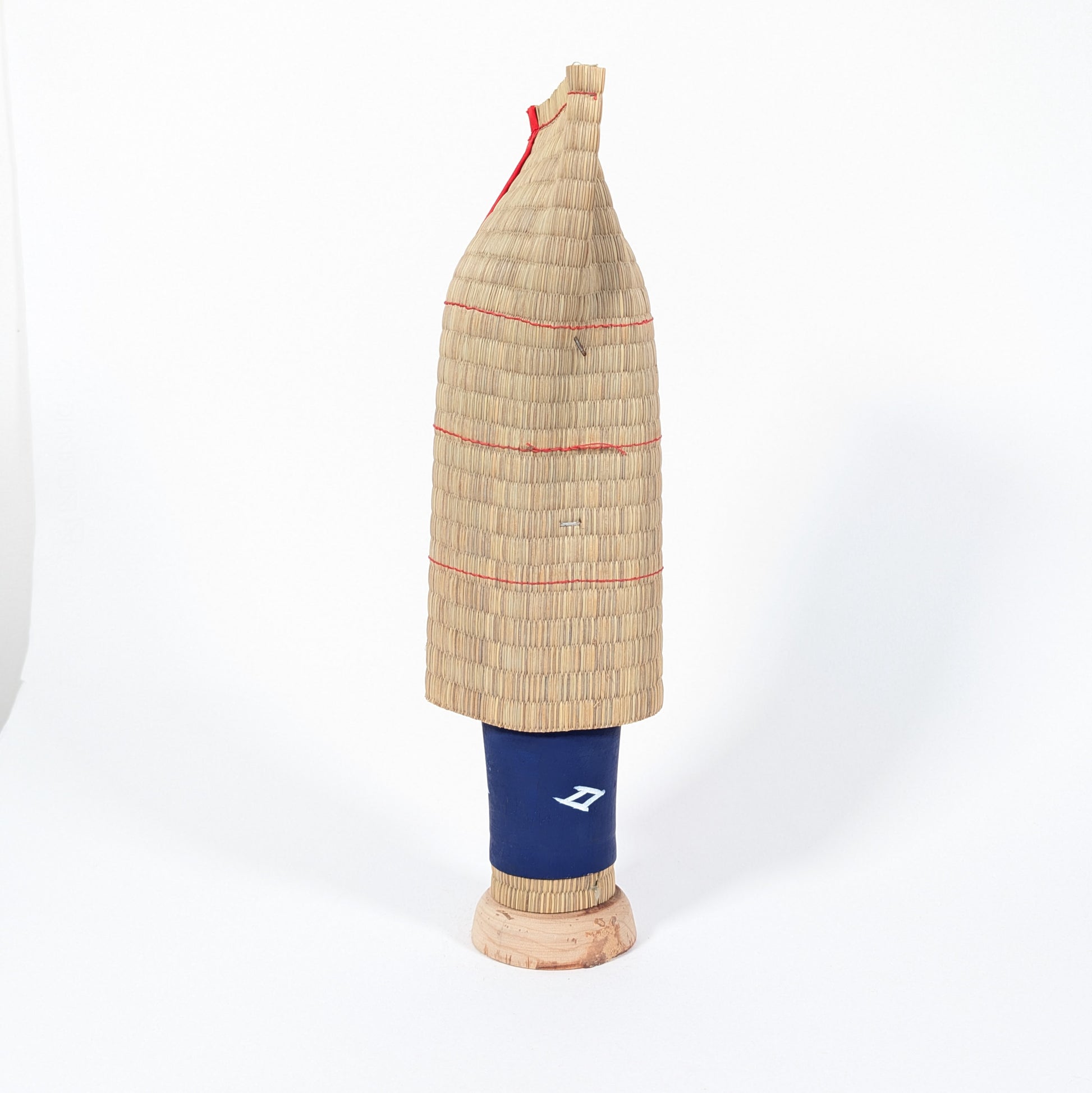 Dos d’une kokeshi japonaise avec manteau traditionnel mino en paille, protection contre la neige en montagne au Japon