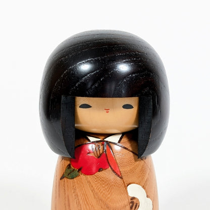 Gros plan du visage minimaliste d’une kokeshi Usaburo Haru no uta avec cheveux noirs laqués et expression douce