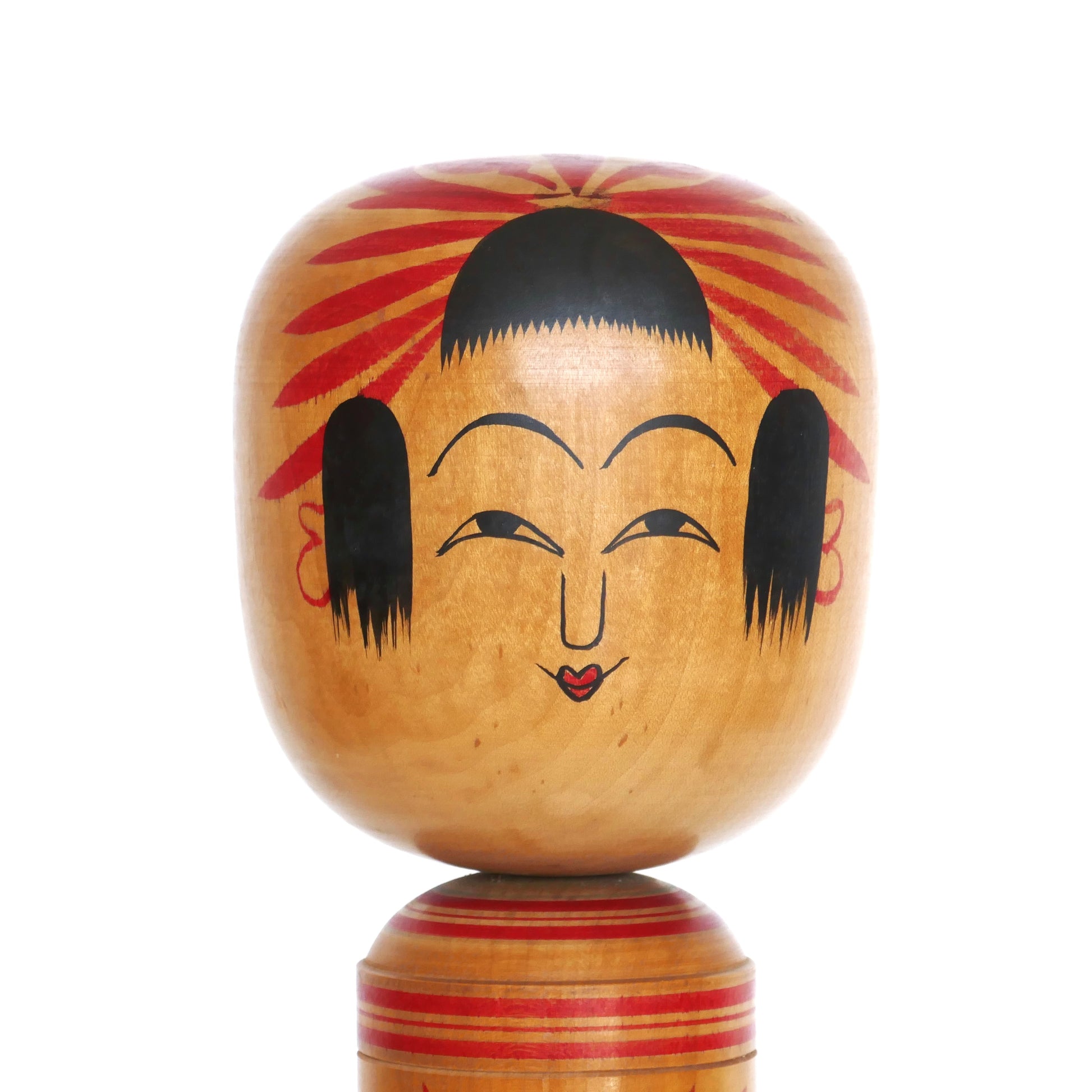 Gros plan sur le visage d’une kokeshi Hijiori : sourcils arqués, yeux en amande, bouche rouge en V, caractéristiques du style Hijiori
