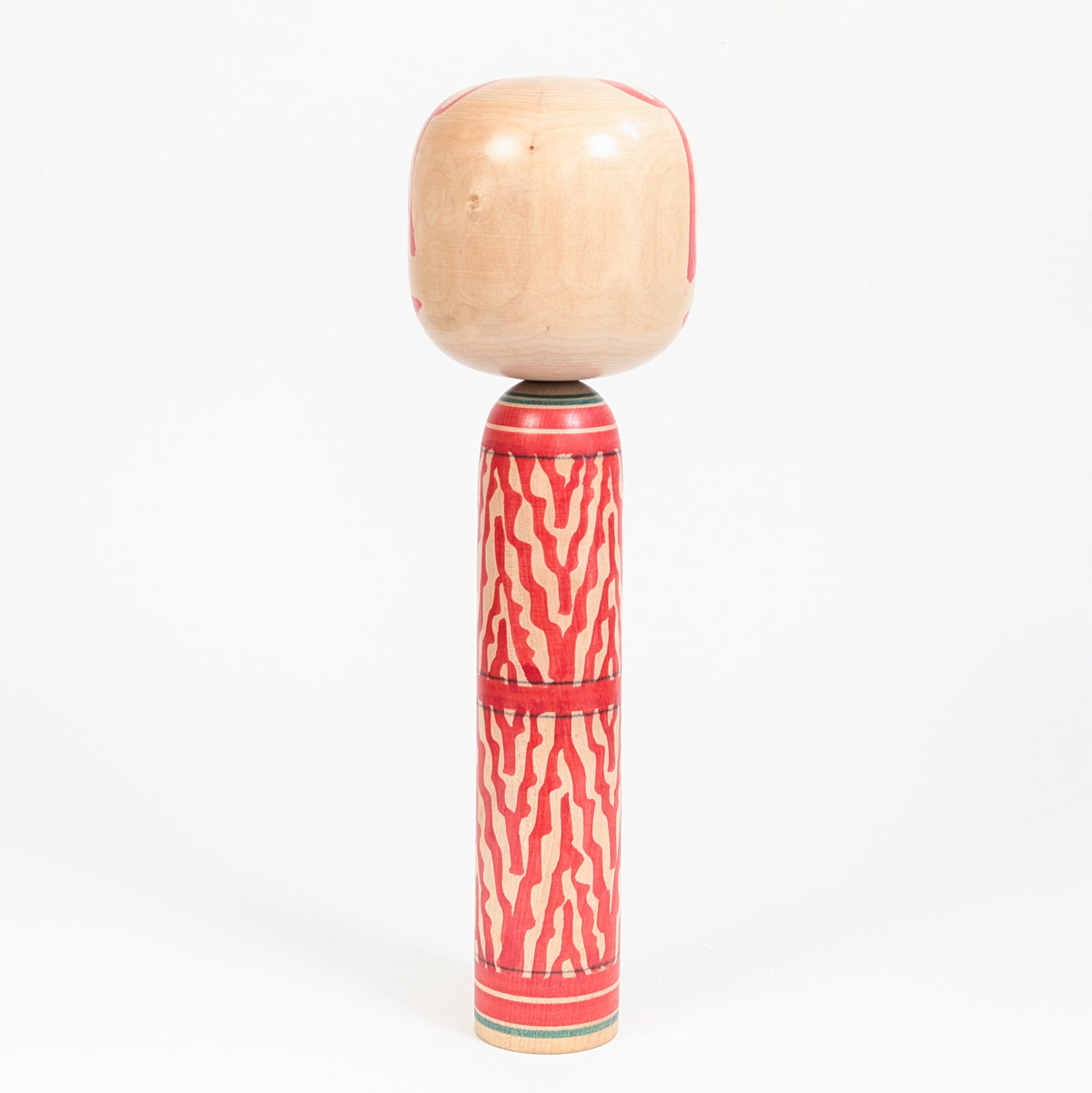 Dos d’une kokeshi japonaise Togatta en bois tourné, décor mokume rouge et bois naturel, artisanat traditionnel du Tohoku