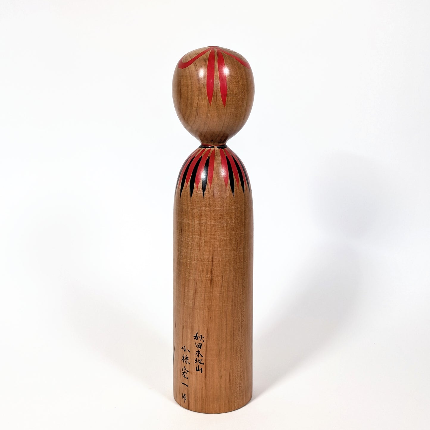 Dos d’une kokeshi japonaise traditionnelle en bois de yamazakura, finition naturelle artisanale