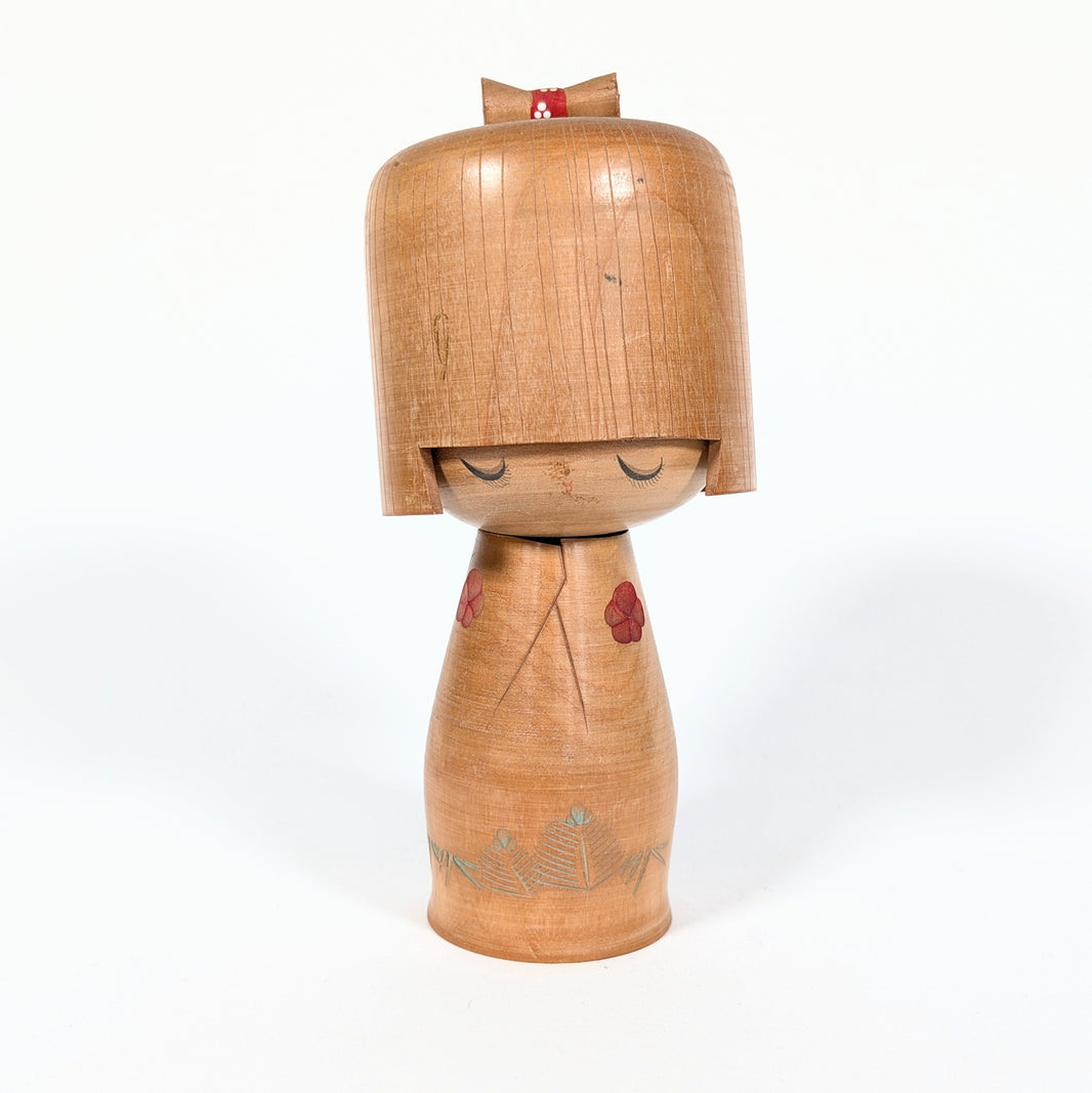 Kokeshi japonaise vintage Hōshun par Ueda Izumi, visage aux yeux fermés, coiffure géométrique et fleurs de ume rouges