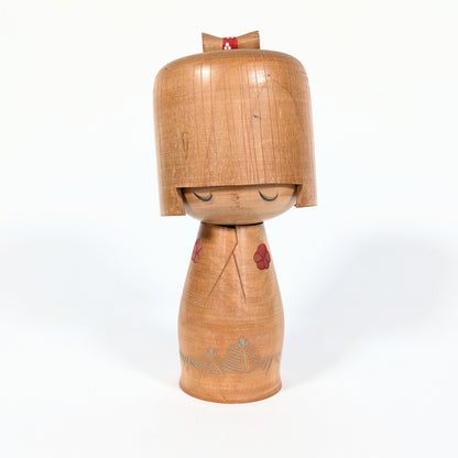 Kokeshi japonaise vintage Hōshun par Ueda Izumi, visage aux yeux fermés, coiffure géométrique et fleurs de ume rouges
