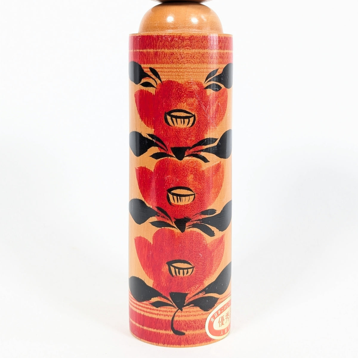 Détail du corps d’une kokeshi japonaise en bois tourné, décor tsubaki rouge et noir peint à la main