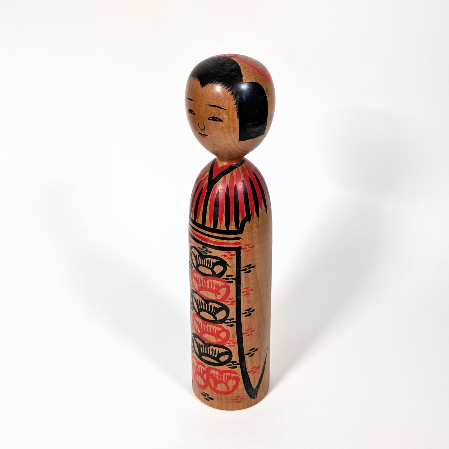 Vue de profil d’une kokeshi japonaise artisanale, kimono peint à la main, école Kijiyama Akita