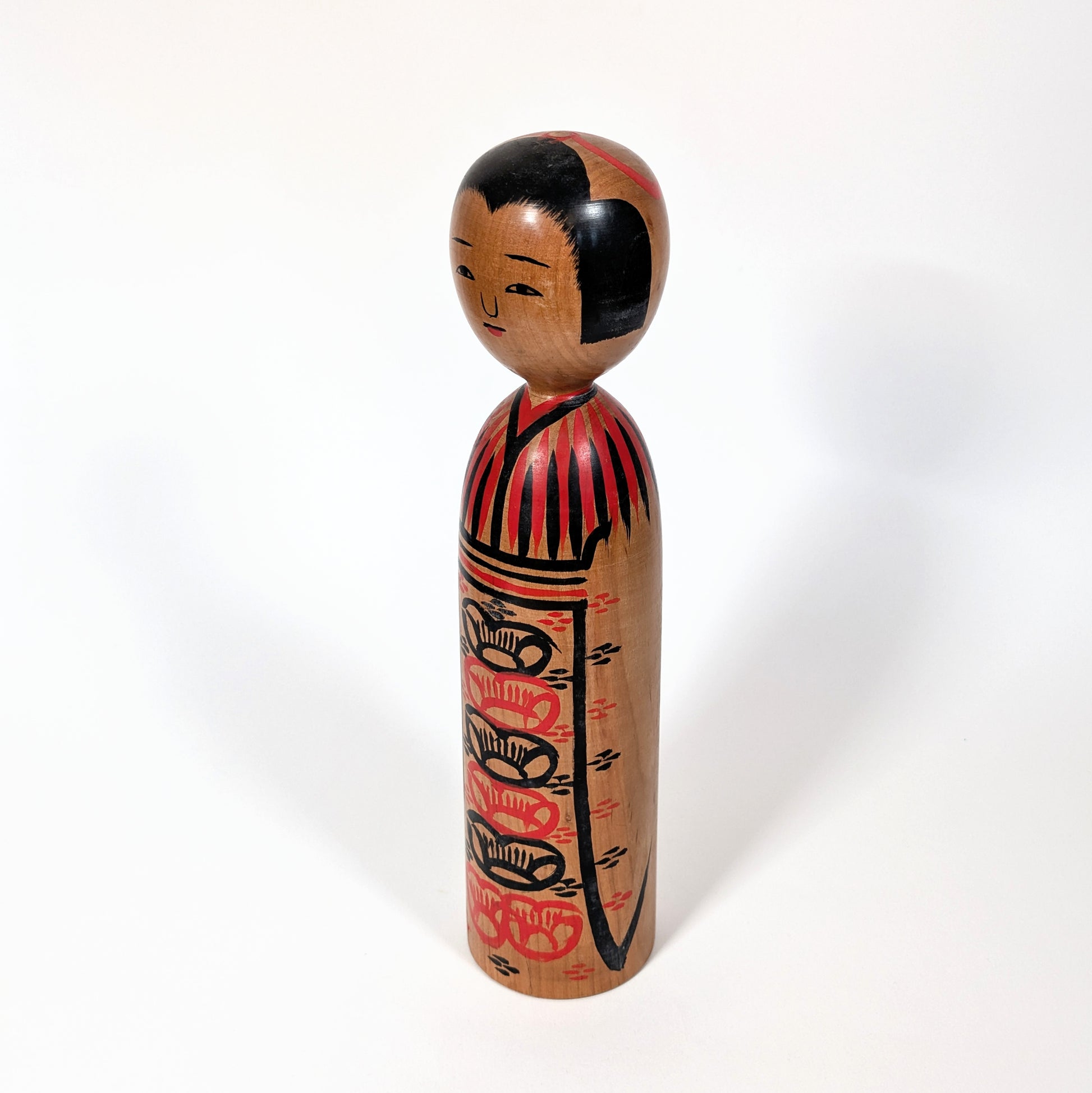 Vue de profil d’une kokeshi japonaise artisanale, kimono peint à la main, école Kijiyama Akita