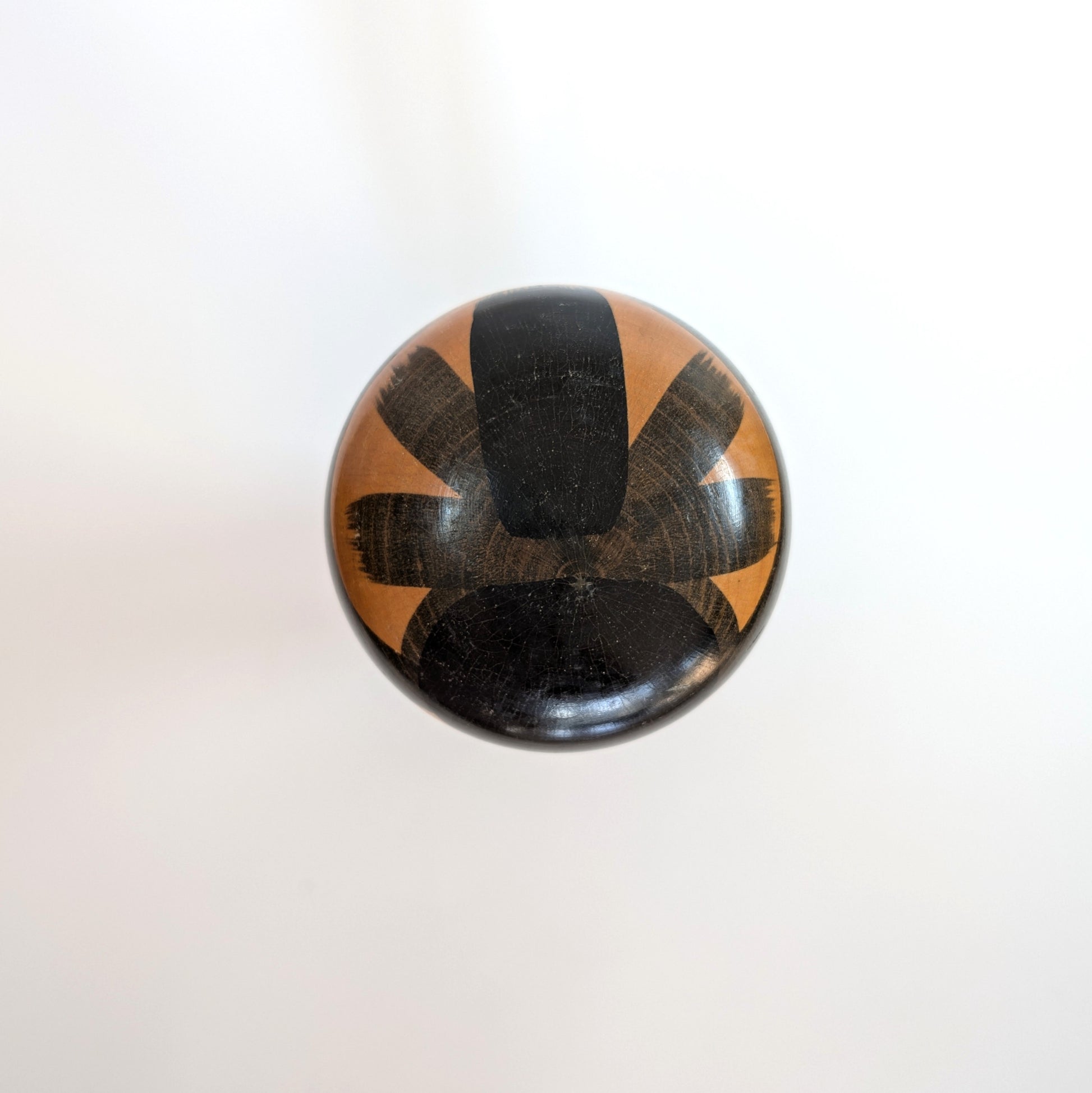 Vue du dessus de la tête d’une kokeshi japonaise en bois peint, coiffure noire stylisée – Sasaki Katsumi