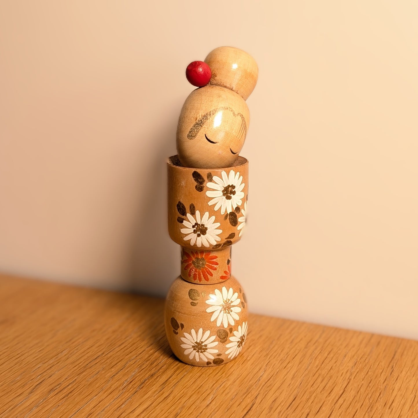 Kokeshi japonaise vintage d’Ishida Tomio, poupée en bois à décor floral blanc et orange.
