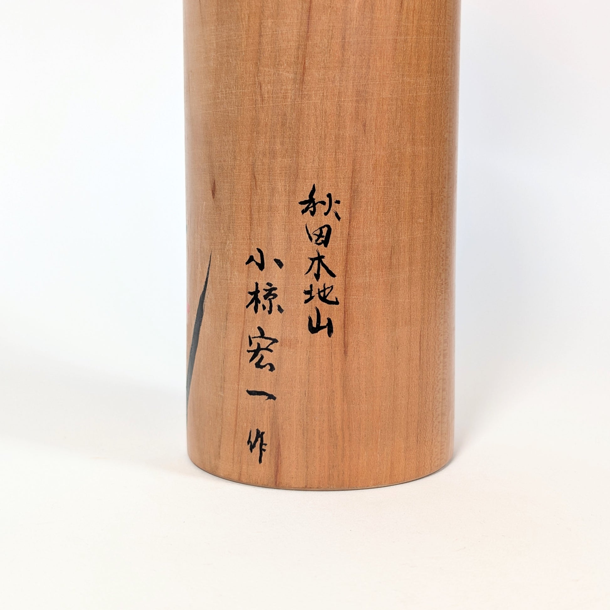 Dos d’une kokeshi japonaise traditionnelle en bois de yamazakura, finition naturelle artisanale
