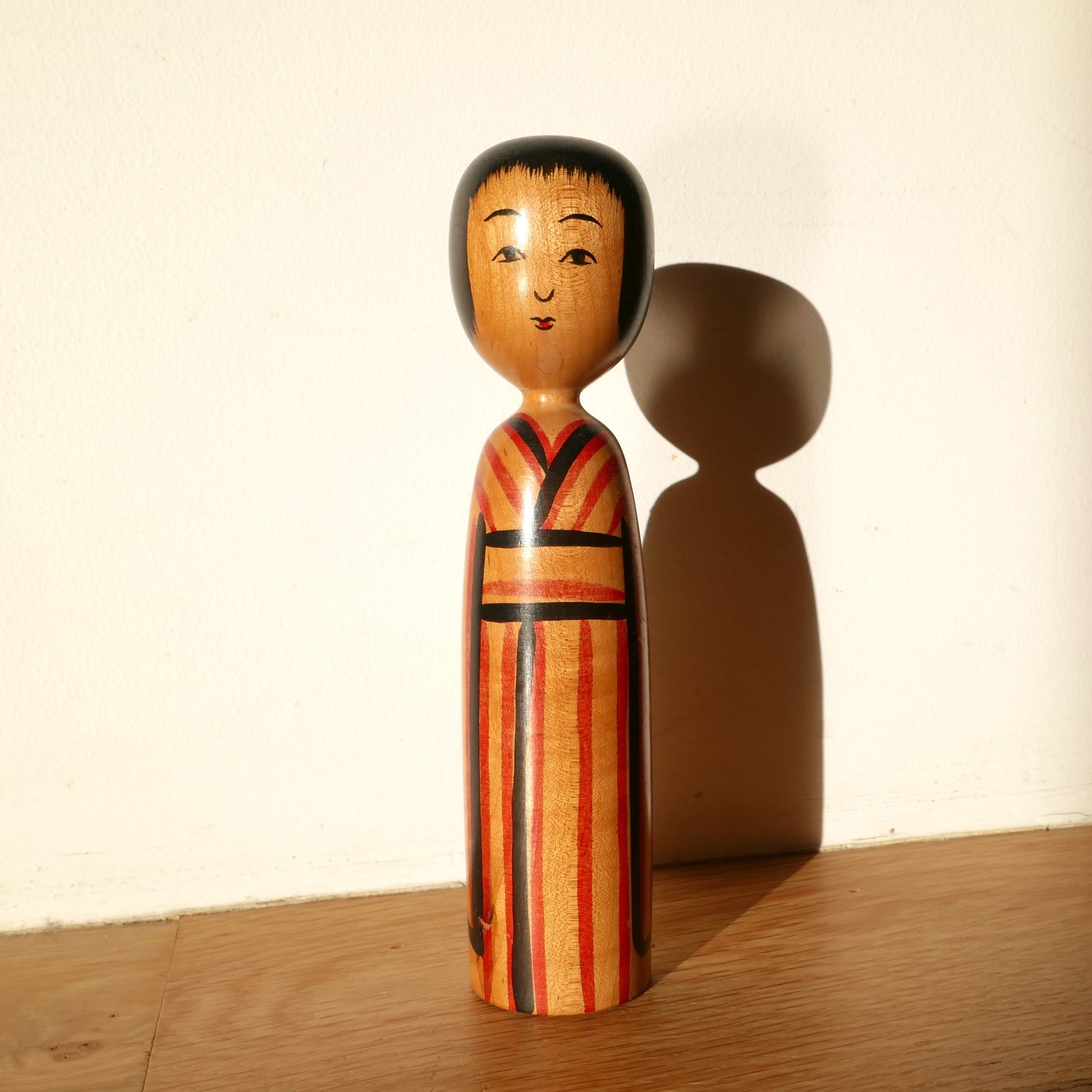 Kokeshi japonaise Kijiyama vue de face, signée Takahashi Yuji – poupée traditionnelle en bois peint sous lumière naturelle avec ombres