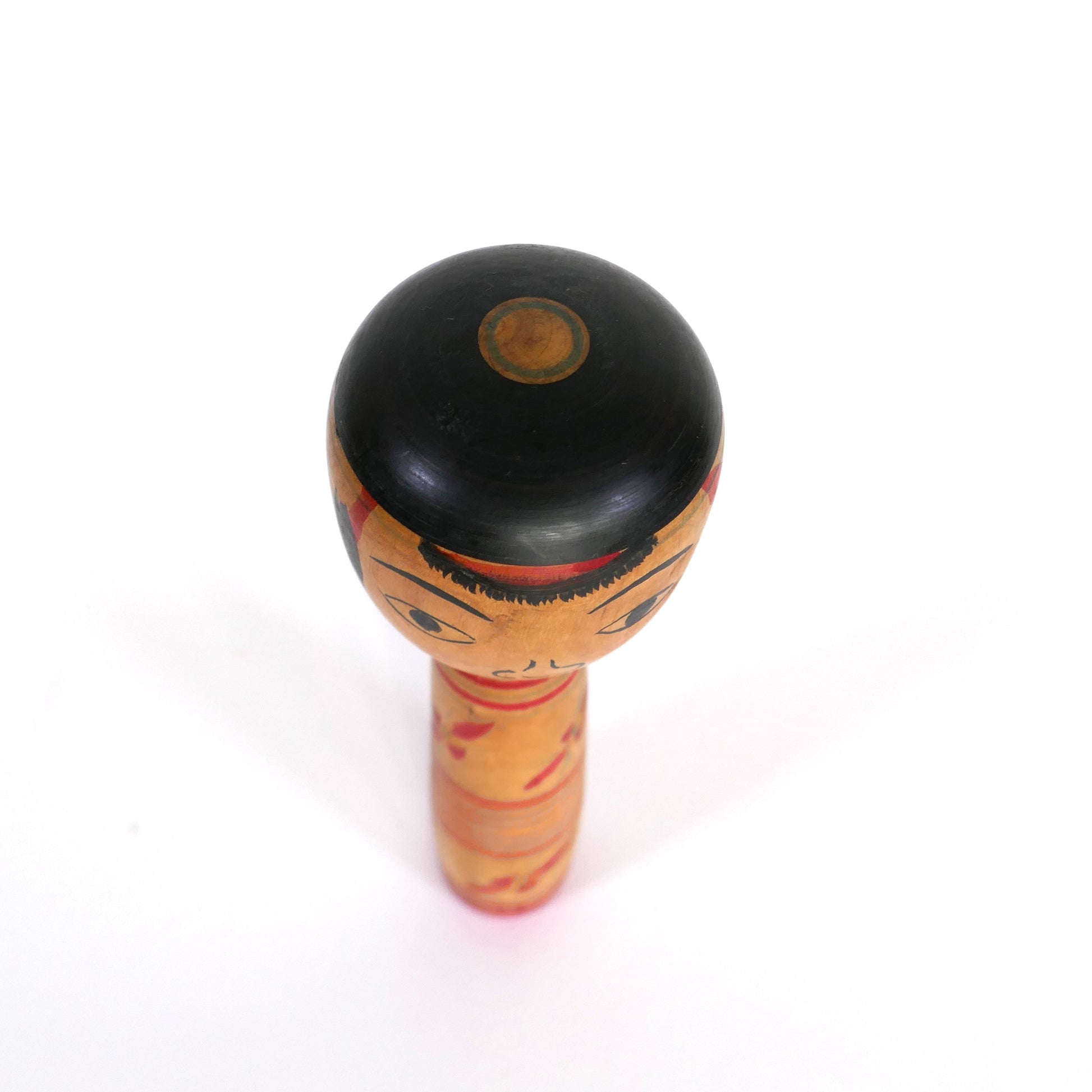 Vue du dessus d'une kokeshi japonaise ancienne Nakanosawa – cheveux noirs circulaires avec motif central.
