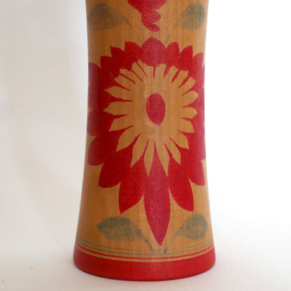 Motif de chrysanthème rouge en forme de diamand hishigiku peint sur le corps d’une kokeshi Naruko, style traditionnel japonais. 