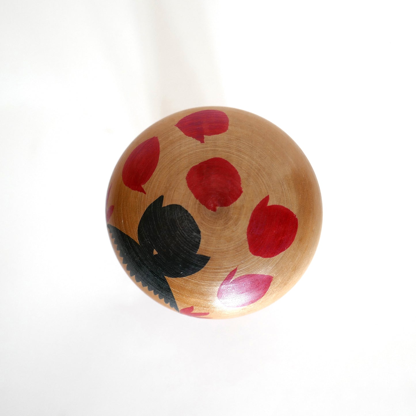 Dessus de la tête d’une kokeshi Naruko, décorée de motifs floraux rouges, œuvre de Kojima Chōjirō.
