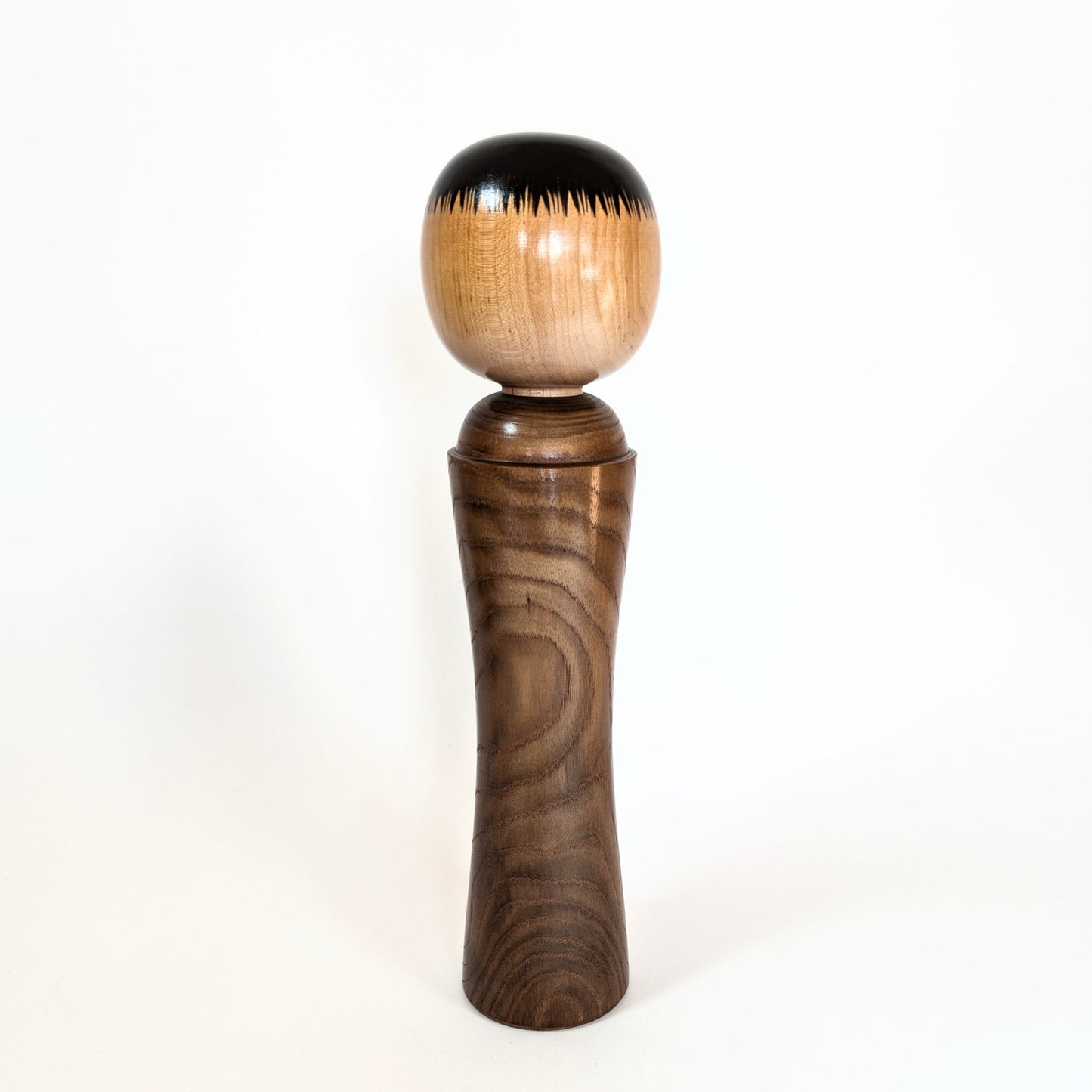 Vue arrière d'une kokeshi japonaise artisanale, coiffure noire typique du style Naruko Ginzan