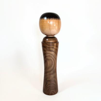 Vue arrière d'une kokeshi japonaise artisanale, coiffure noire typique du style Naruko Ginzan