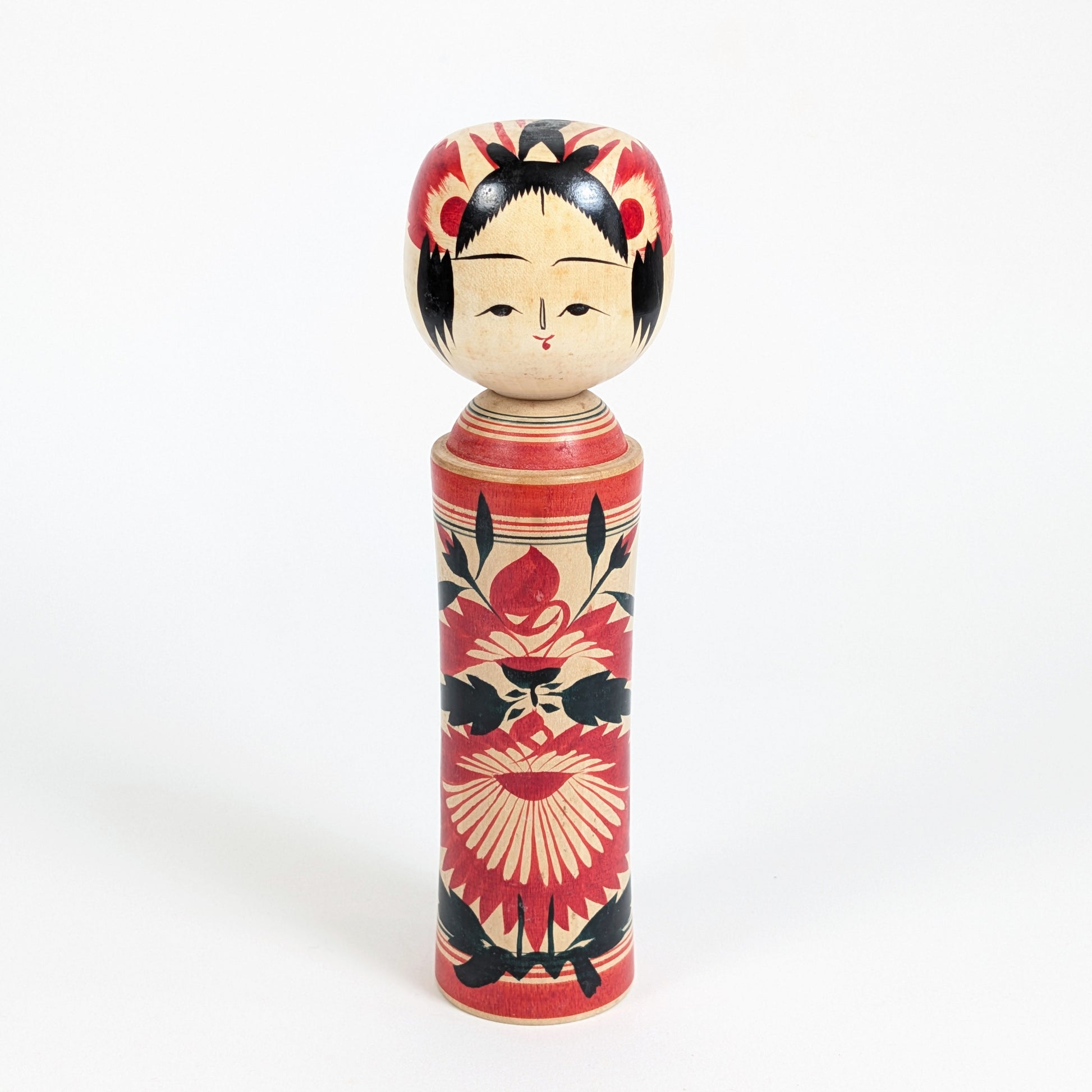 Kokeshi traditionnelle Naruko de Suzuki Toshiyuki 鈴木 俊幸 , poupée japonaise en bois ornée de grands motifs floraux rouges et noirs.