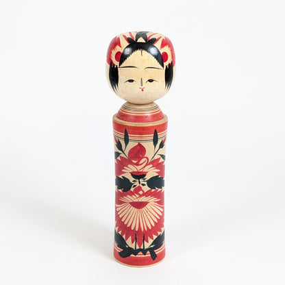 Kokeshi traditionnelle Naruko de Suzuki Toshiyuki 鈴木 俊幸 , poupée japonaise en bois ornée de grands motifs floraux rouges et noirs.