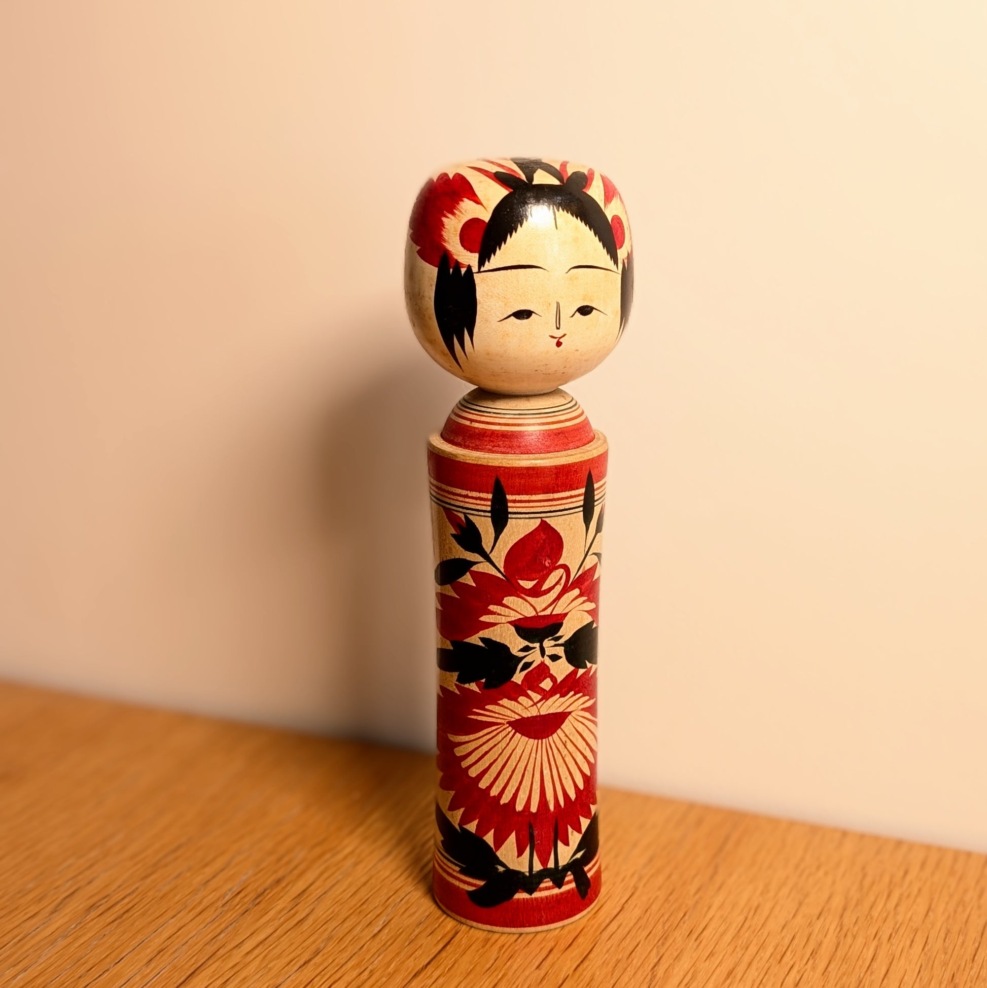 Kokeshi Naruko vintage de Suzuki Toshiyuki présentée en décoration, poupée japonaise en bois à motifs floraux rouges et noirs.