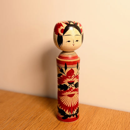 Kokeshi Naruko vintage de Suzuki Toshiyuki présentée en décoration, poupée japonaise en bois à motifs floraux rouges et noirs.
