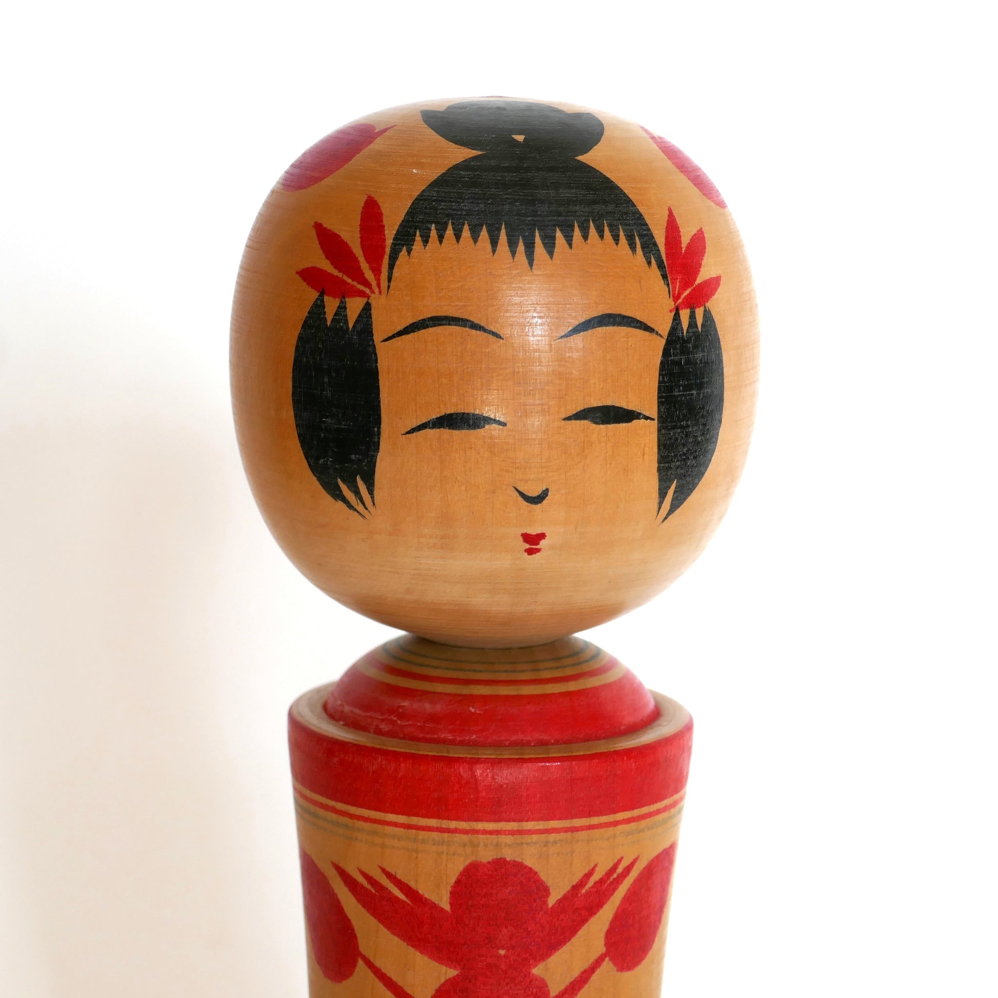 Gros plan sur le visage d’une kokeshi Naruko peinte à la main, artisanat japonais traditionnel.