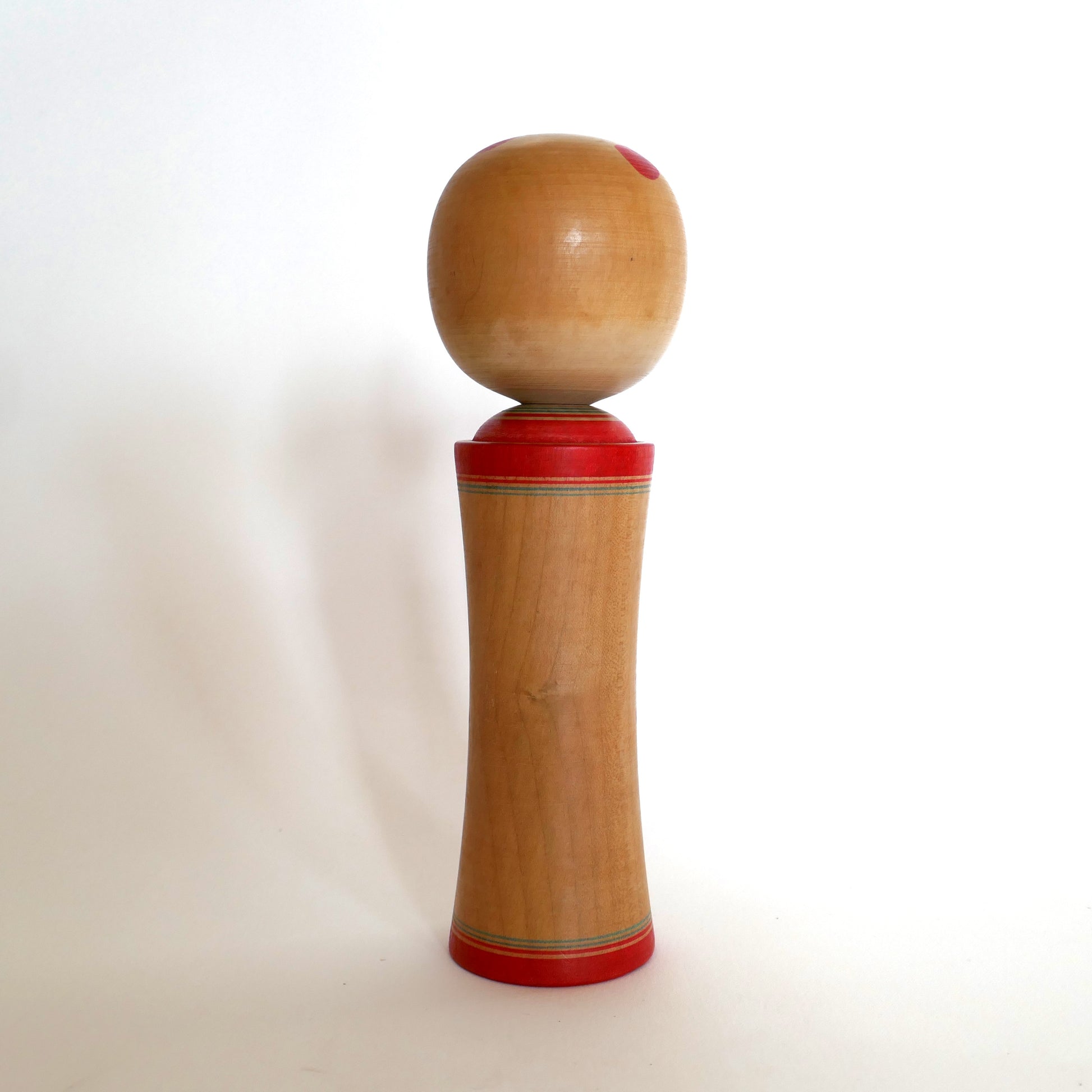 Vue de dos d’une kokeshi Naruko, poupée en bois japonaise artisanale.
