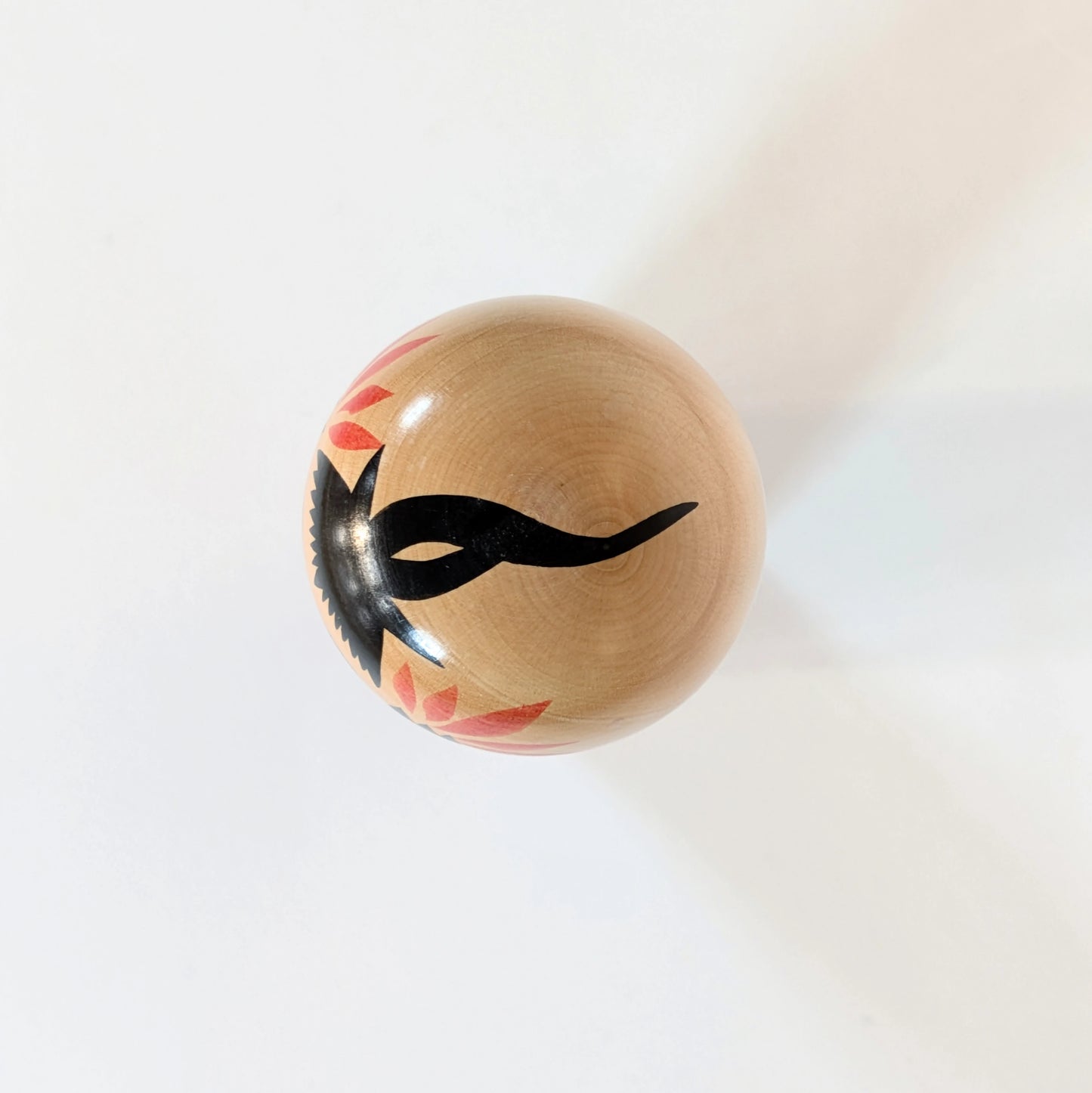 Vue du dessus d’une kokeshi Naruko montrant le motif noir peint sur la tête, représentant la chevelure.