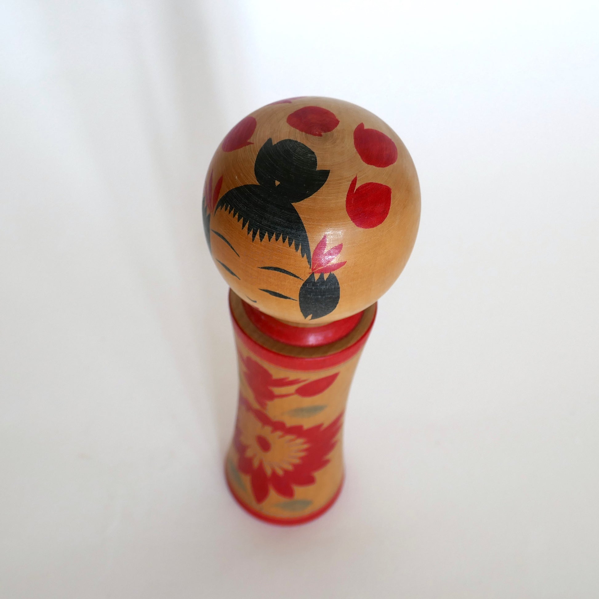Vue plongeante d’une kokeshi Naruko, poupée japonaise vintage de la période Shōwa.