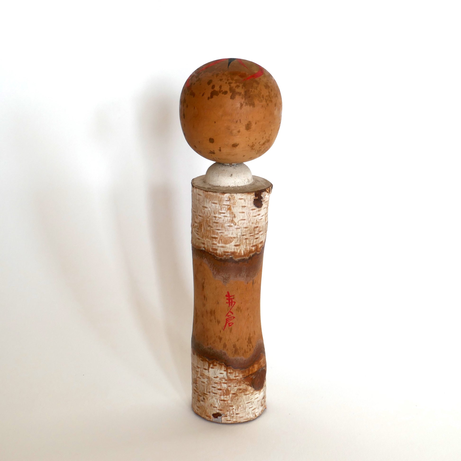 Vue arrière d’une kokeshi japonaise avec inscription en kanji rouge indiquant Akakura, station de montagne japonaise.