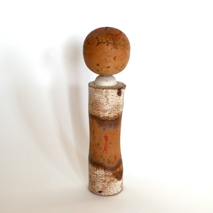 Vue arrière d’une kokeshi japonaise avec inscription en kanji rouge indiquant Akakura, station de montagne japonaise.