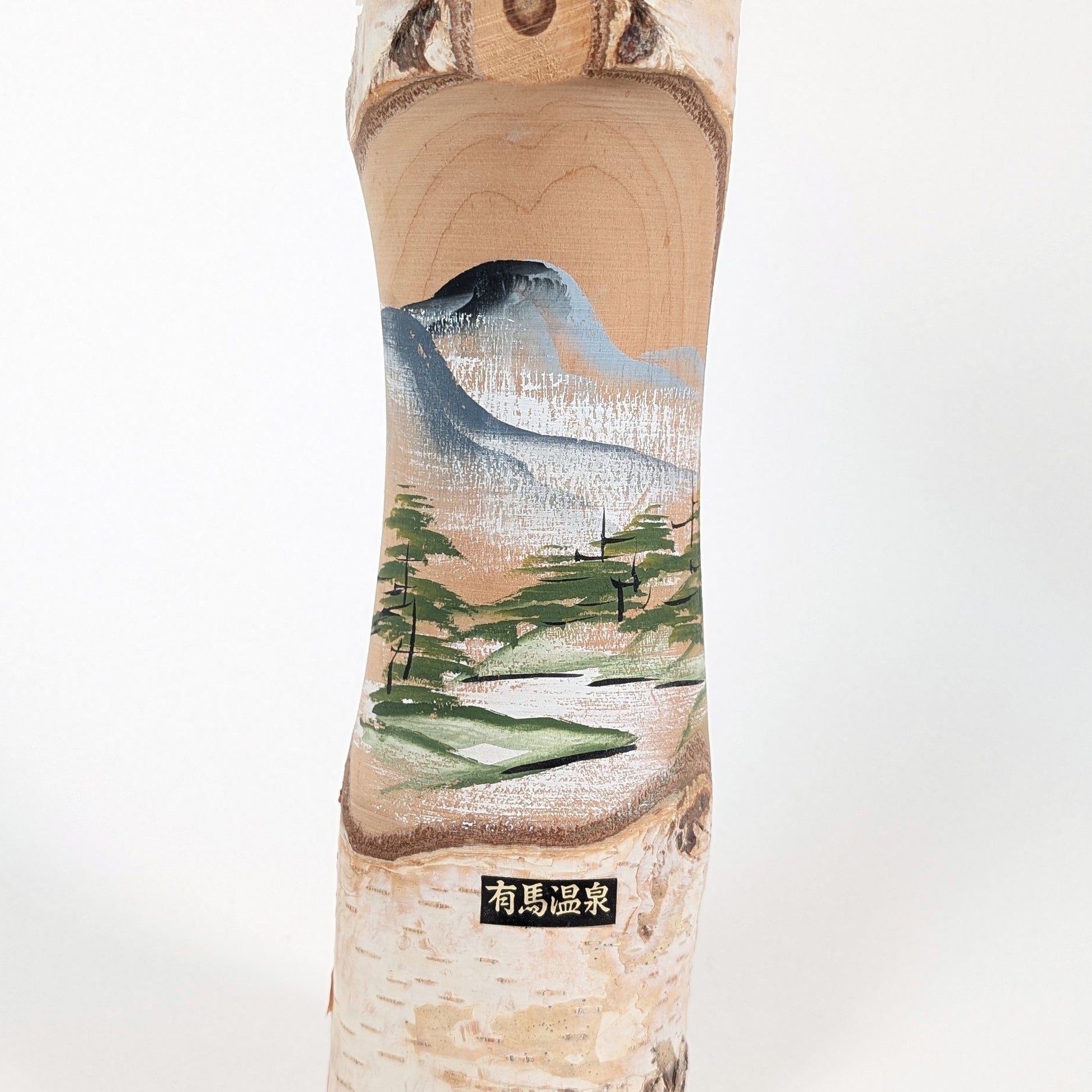 Kokeshi omiyage japonaise d’Arima Onsen avec paysage peint de rivière, montagnes et pins sur bois naturel