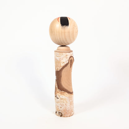 Dos d’une kokeshi omiyage en bois brut avec écorce naturelle, bel exemple d’artisanat populaire japonais