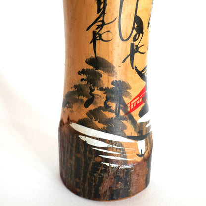 Détail d’un pont rouge dans un paysage peint sur une kokeshi japonaise – style omiyage avec rivière et forêt en lavis d’encre