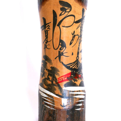 Détail d’une kokeshi souvenir peinte à la main – paysage de montagne, pont rouge et pagode avec calligraphie japonaise stylisée