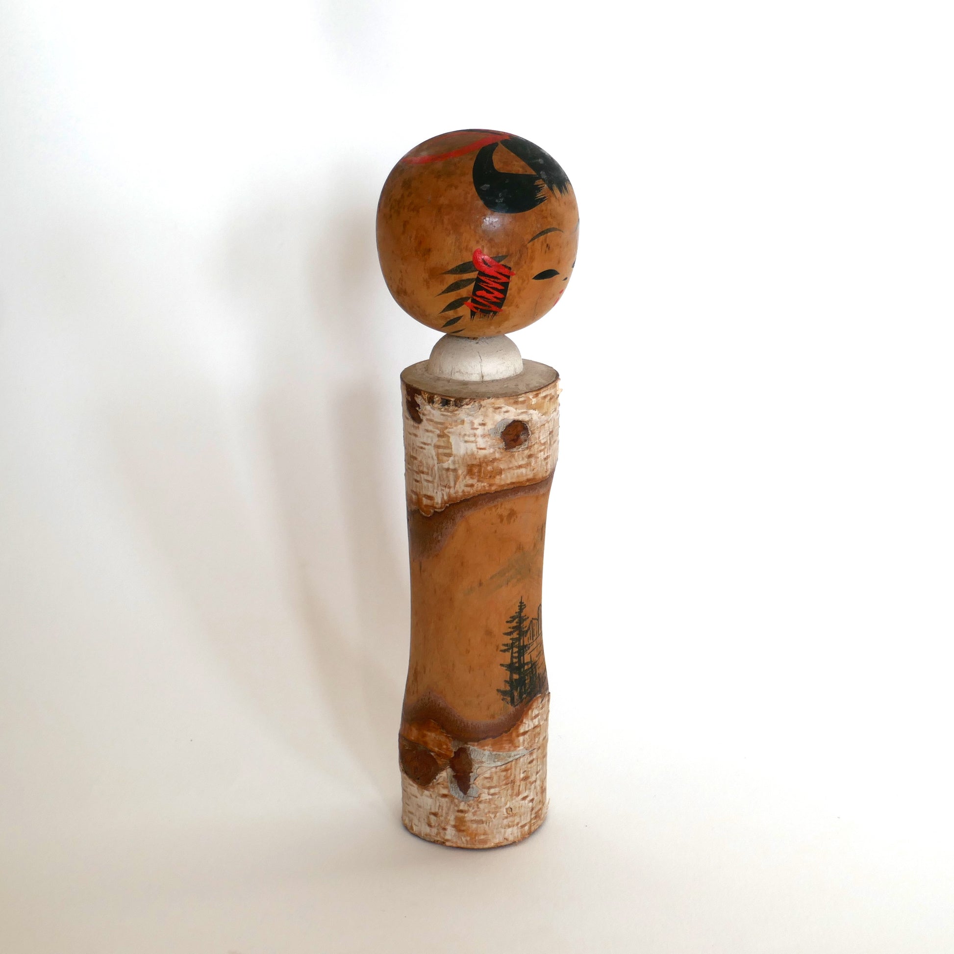 Kokeshi poupée japonaise de type omiyage vue de profil droit, décorée d’un paysage montagnard.