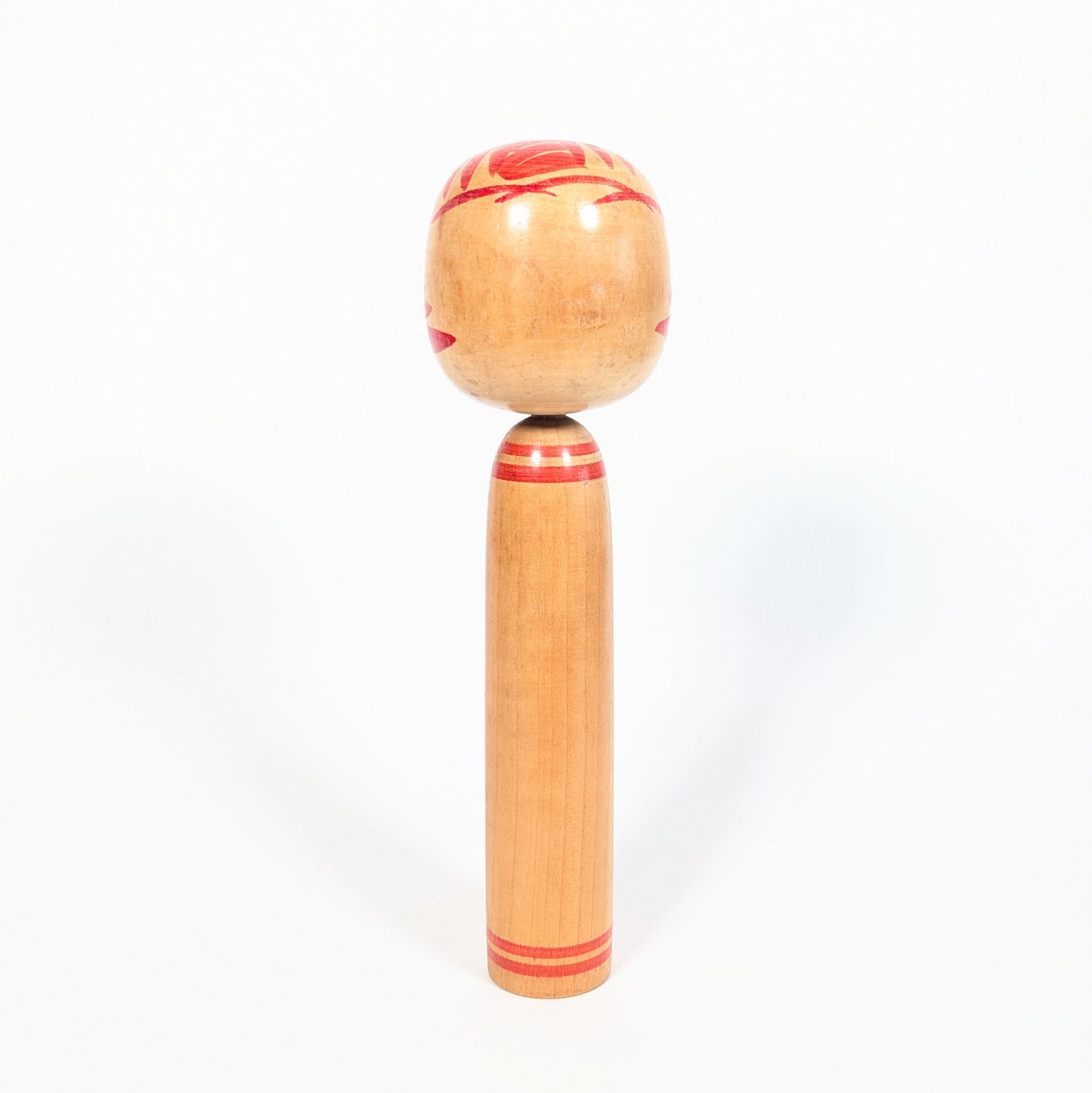 Dos de kokeshi Onuma Shoji en bois tourné, anneaux rouges au cou et à la base, décor kasanegiku visible sur les côtés.