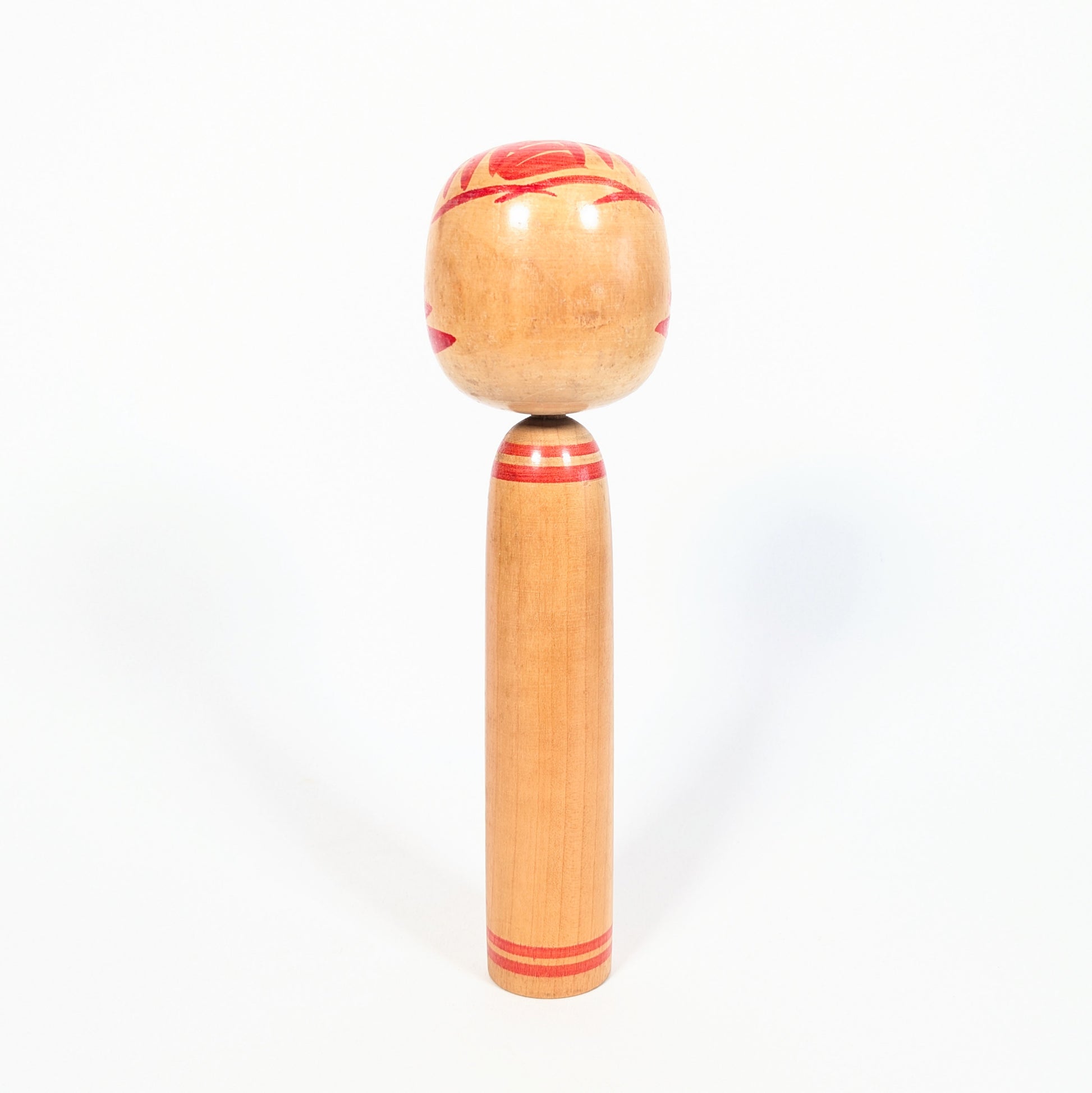Dos de kokeshi Onuma Shoji en bois tourné, anneaux rouges au cou et à la base, décor kasanegiku visible sur les côtés.