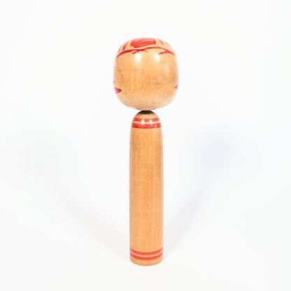 Dos de kokeshi Onuma Shoji en bois tourné, anneaux rouges au cou et à la base, décor kasanegiku visible sur les côtés.