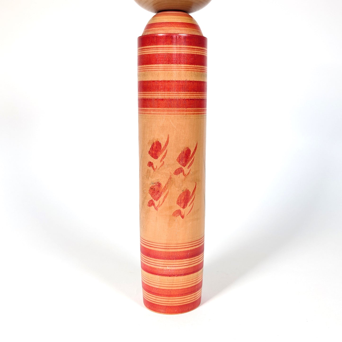 Détail du corps d’une kokeshi Sakunami avec motifs floraux peints à la main sur bois