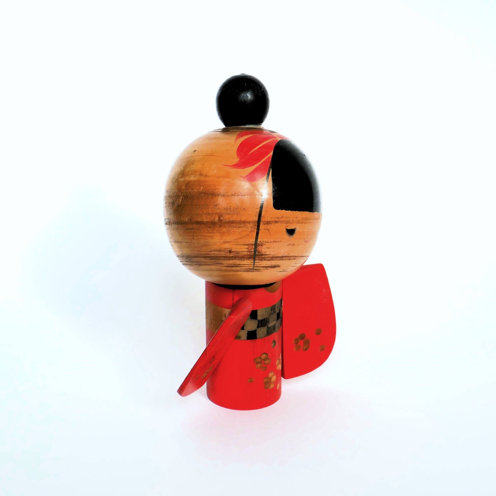 Kokeshi artisanale de profil droit, mettant en valeur le dessin du visage et la manche.