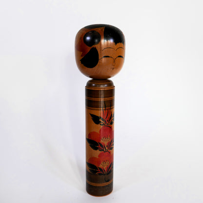 Kokeshi japonaise Shingata artisanale par Kiyohara Takao, décor de camélias rouges et feuilles noires, vue de profil.