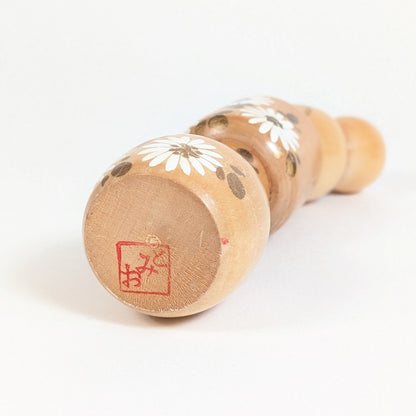 Dessous d’une kokeshi signée Ishida Tomio avec cachet rouge de l’artisan japonais sous la base en bois.