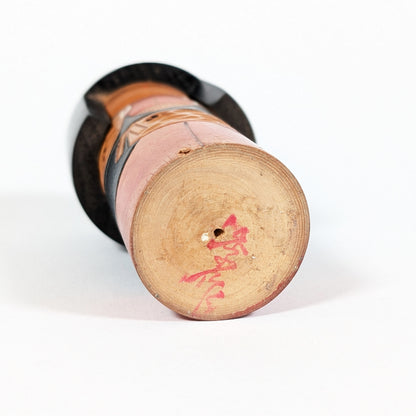 Signature Kisaku 季作 sous une kokeshi japonaise, marque d’artiste gravée sur le bois