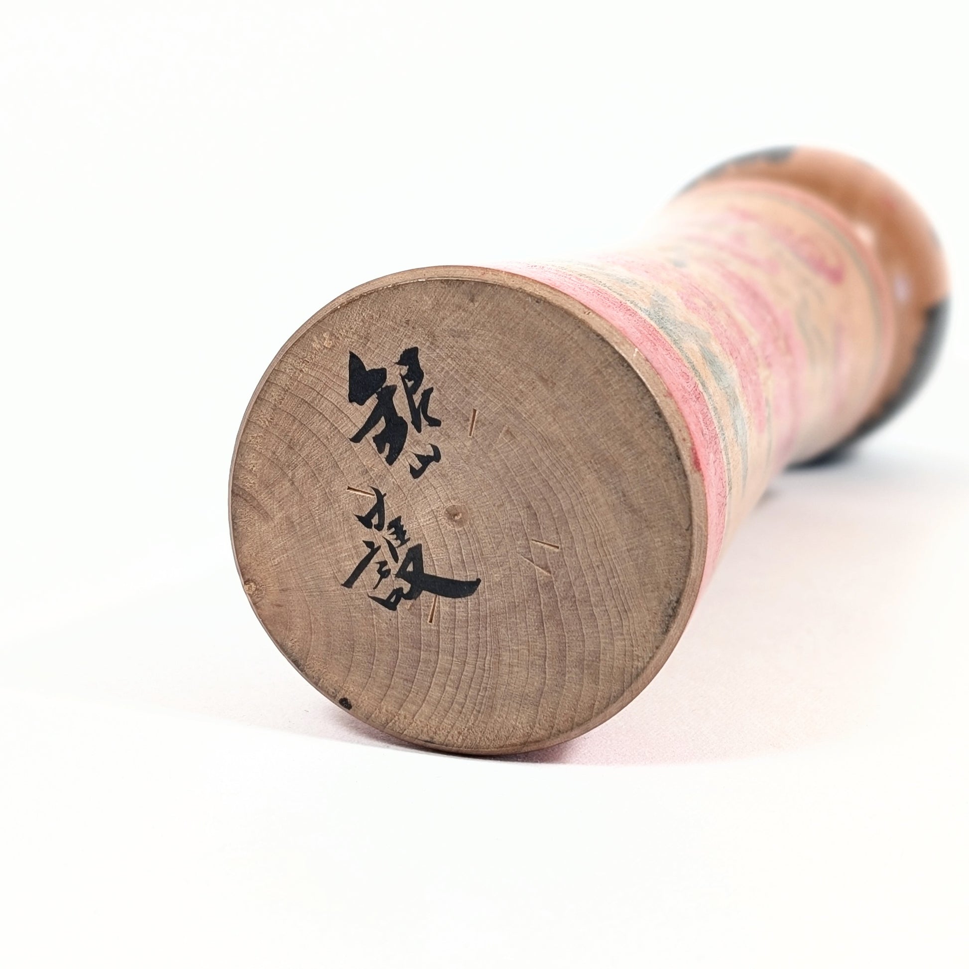 Signature sous la base d’une kokeshi Mamoru Izu, poupée japonaise artisanale signée de style Oshin Ginzan