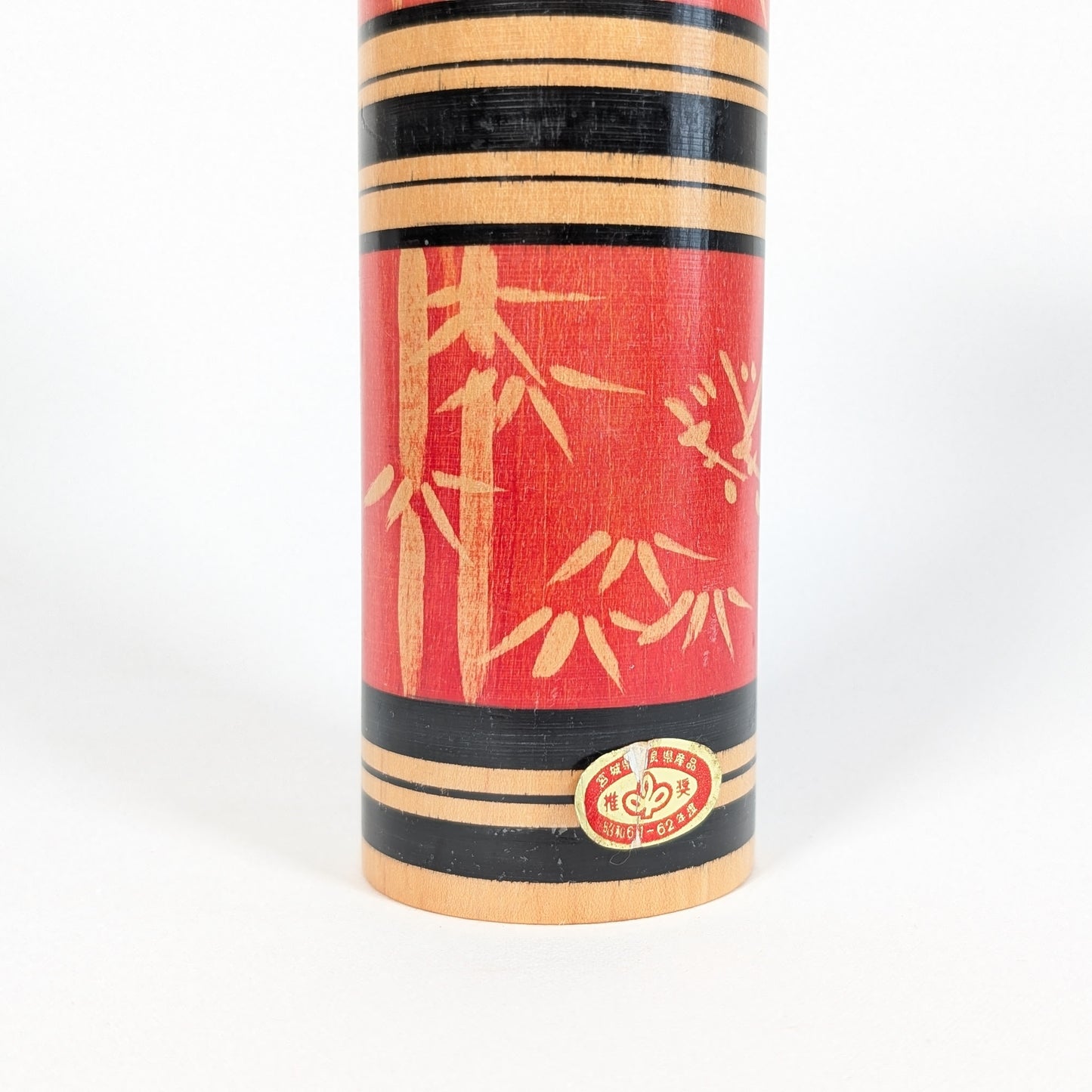 Détail de l’étiquette d’origine sur une kokeshi sosaku japonaise rouge décor bambou