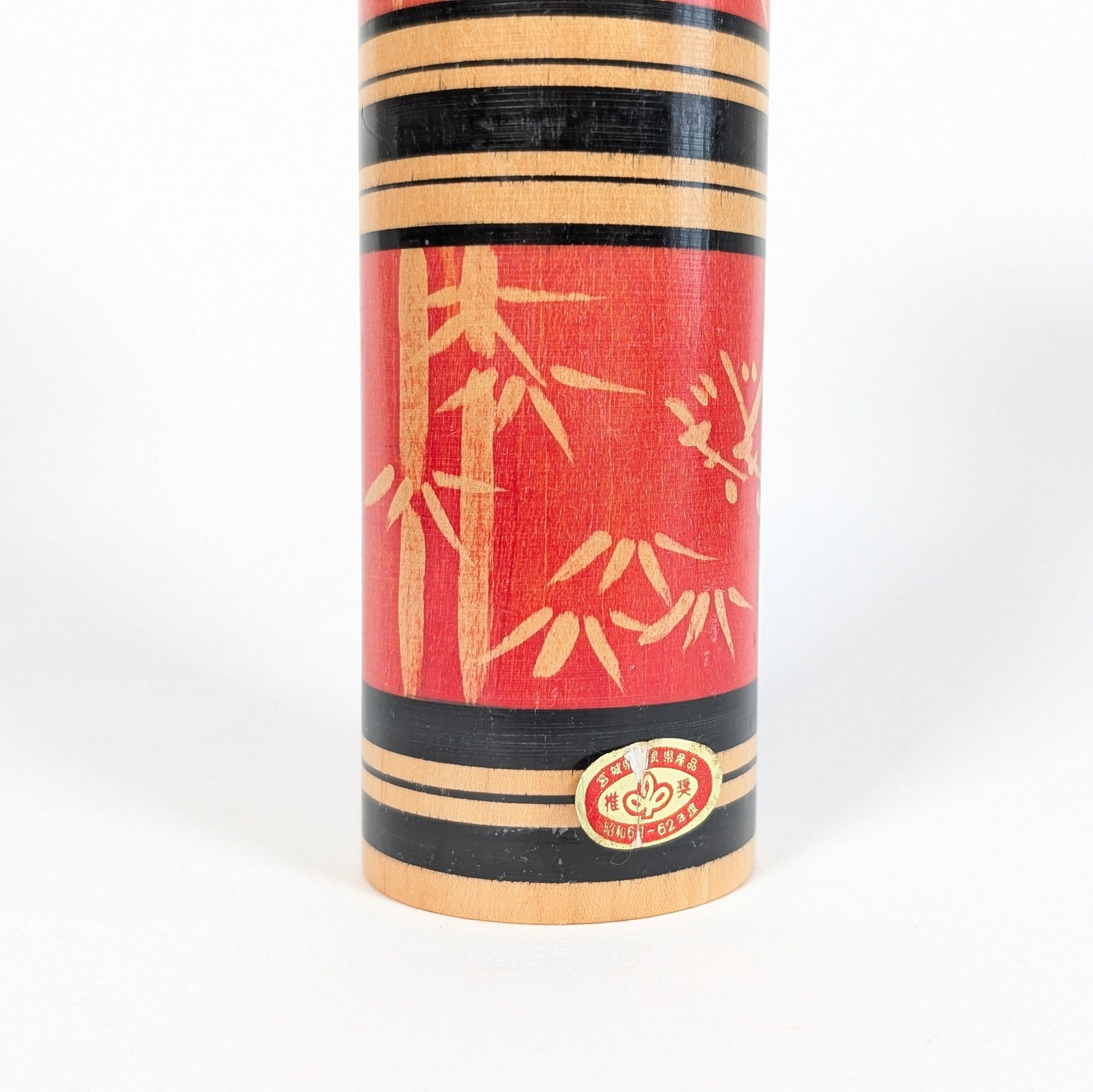 Détail de l’étiquette d’origine sur une kokeshi sosaku japonaise rouge décor bambou