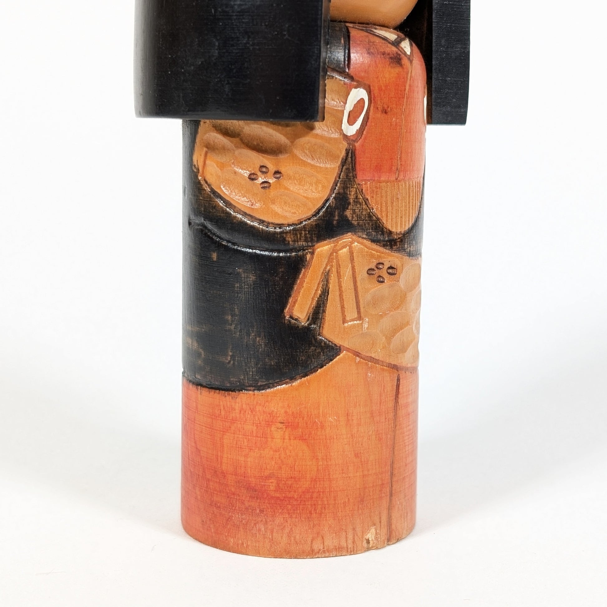 Détail latéral d’une kokeshi sosaku avec motifs japonais sculptés dans le bois