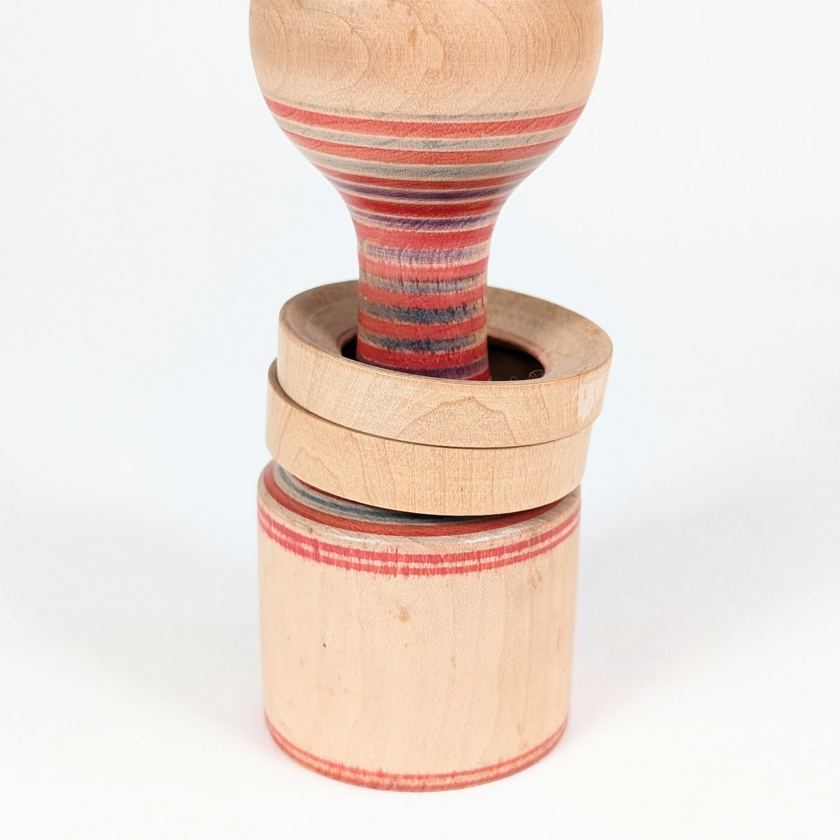 Gros plan sur les deux anneaux mobiles d’une Yamiyo kokeshi Tōgatta, technique japonaise de tournage sur bois.