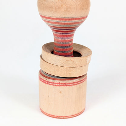 Gros plan sur les deux anneaux mobiles d’une Yamiyo kokeshi Tōgatta, technique japonaise de tournage sur bois.